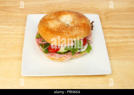 Ham salad bagel on a plate on a wooden tabletop Stock Photo