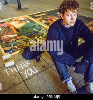 Manchester, England, Uk February 1989: A young pavement artist sits beside his drawings on Market Street. Taken on medium format film transparency. Stock Photo