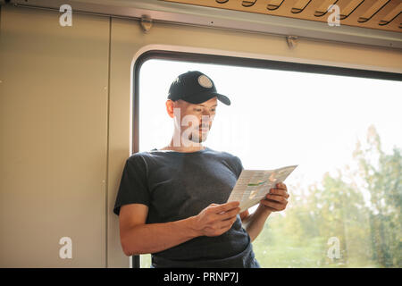 Tourist at the window in the train looks the map. Stock Photo