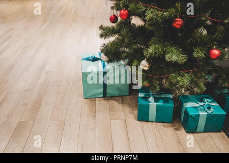 Photo of gift boxes under Christmas tree, New Year home decorations, wrapping of Santa presents, festival fir tree decorated with garland, baubles and Stock Photo