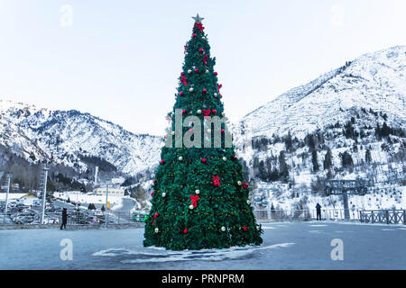 Decorated with beautiful balls and garlands the new year tree standing on mountains in the background. Stock Photo