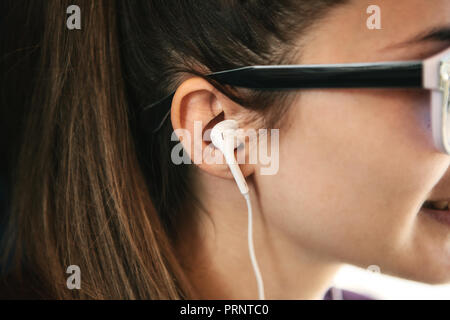 Close-up of a girl with headphones listening to music or a podcast. Stock Photo
