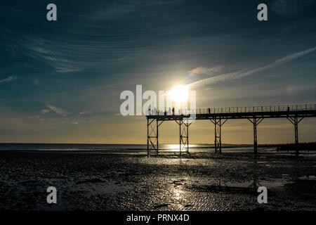 silhouette people at sunset and low tide on bognor regis victorian english pier Stock Photo