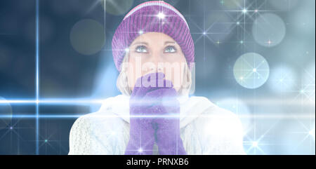Composite image of freezing young woman wearing gloves looking upwards Stock Photo