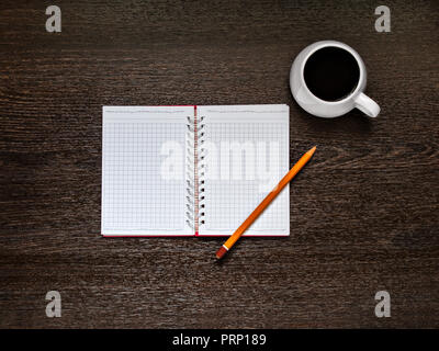 On a wooden background there is an open notebook, a yellow pencil, a white cup with coffee. Horizontally with copy space Stock Photo