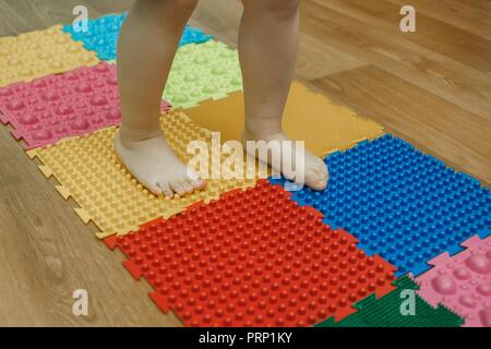 Toddler on baby foot massage mat. Exercises for legs on orthopedic