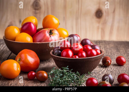 Colorful tomatoes on rural wooden table, autumn harvest time, organic farmer vegetables Stock Photo