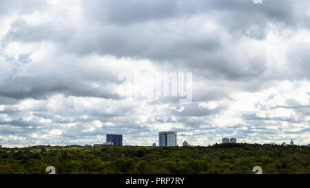 gray rainy clouds in sky over apartment houses and woods in autumn day Stock Photo