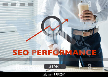 cropped view of developer holding laptop and coffee to go, with SEO performance Stock Photo