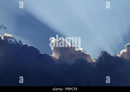 angry storm clouds gathering in late August in Italy with the sun's rays shining behind Stock Photo