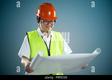 Portrait of professional construction contractor worker with hard hat and holding construction blue print plan with light blue background . Stock Photo