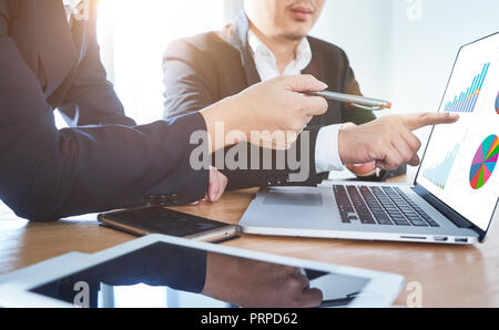 Two businessmen discussing the charts and graphs showing the results of their successful project .Digital tablet ,smart phone and laptop computer usin Stock Photo