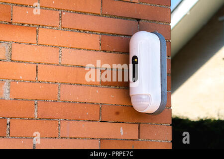 Surveillance Camera With Movement Detector on Red Brick House Stock Photo