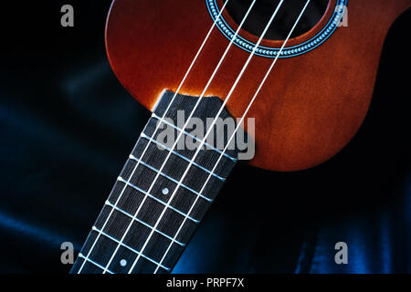 closeup photo of a ukulele against a black leather background Stock Photo