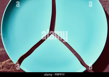 Plate broken into three pieces, color toned picture. Stock Photo