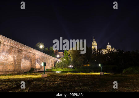 Night view of Roman bridge over Tormes river in Salamanca, illuminated, and Old and New Cathedrals in the far view, Community of Castile and León, Spa Stock Photo