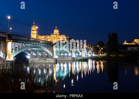 Night view of Salamanca Old and New Cathedrals from Enrique Esteban Bridge over Tormes River, Community of Castile and León, Spain.  Declared a UNESCO Stock Photo