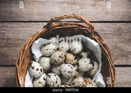 top view of quail eggs in wicker basket on rustic wooden table Stock Photo