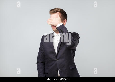 Caucasian man in suit covering his eyes Stock Photo