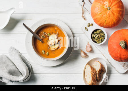 elevated view of pumpkin cream soup with seeds and rusks in bowl on table Stock Photo