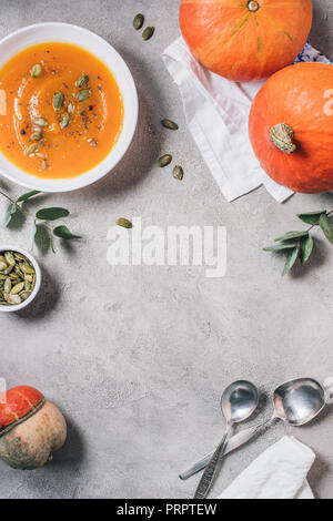 flat lay with pumpkins and plate with pumpkin cream soup on table Stock Photo