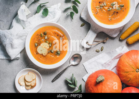 top view of corn cobs, pumpkins, rusks and plates with pumpkin cream soup on table Stock Photo