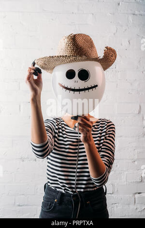 woman holding halloween balloon with straw hat in front of head Stock Photo
