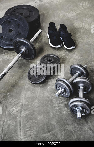 high angle view of various gym equipment and sneakers on concrete floor Stock Photo