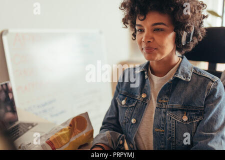 Portrait of african woman working on computer. Female computer programmer working at tech startup. Stock Photo