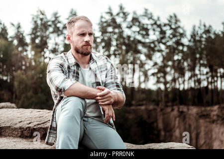 Bearded man feeling thoughtful after personal problems while sitting on his own