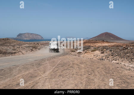 Lanzarote, Canary Islands: a 4x4 on the dirt road to Playa de Las Conchas beach and volcano Montana Bermeja (Scarlet Mountain) of La Graciosa Stock Photo