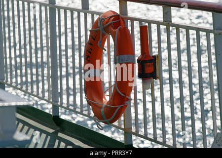 A life ring or lifebuoy attached to railings of a ship, ready to be used to save a drowning person. Stock Photo