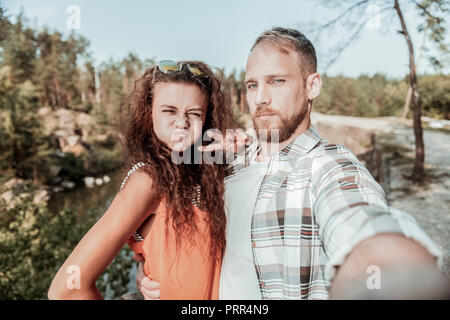 Cute loving couple making very funny faces while making selfie together Stock Photo