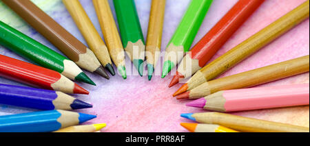 Large colored pencils stacked in a circle close-up on a colored background with colored pencils Stock Photo