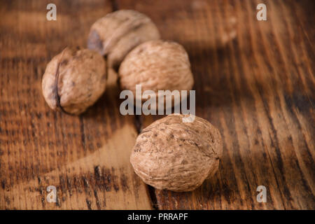 Walnuts spilled on retro wooden desk. Autumn food concept. Close up, selective focus Stock Photo