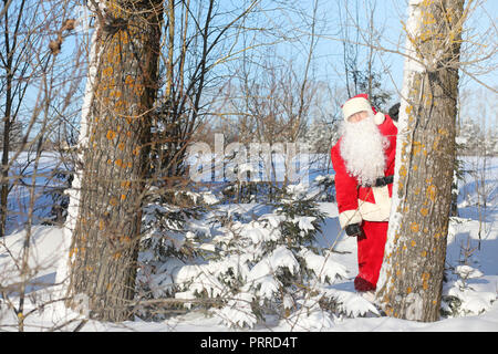 Santa Claus comes with gifts from the outside. Santa in a red su Stock Photo