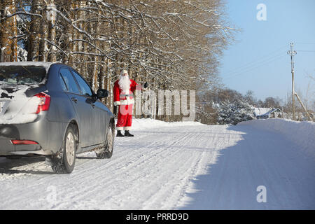 Santa Claus comes with gifts from the outside. Santa in a red su Stock Photo