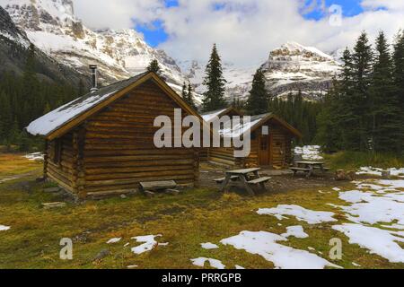 Alpine Club of Canada Wilderness Log Cabin Rustic Shelter and distant snowy mountain Peaks near Lake O’Hara in Yoho National Park Stock Photo