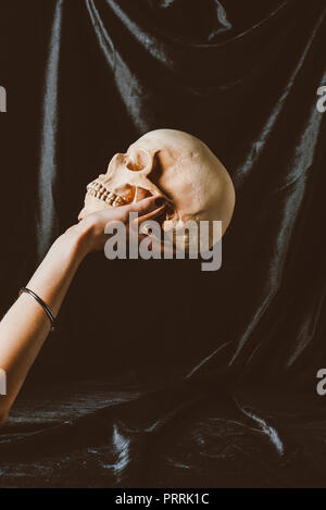 cropped view of woman holding halloween skull on black cloth Stock Photo