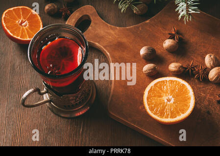 hot mulled wine with spices and orange in glass cup on wooden background Stock Photo