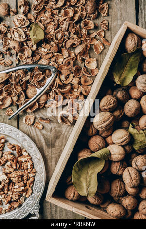 top view of walnuts in box, nutcracker and nutshells on wooden table Stock Photo