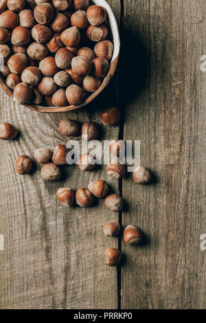 top view of tasty healthy hazelnuts in bowl on wooden table Stock Photo