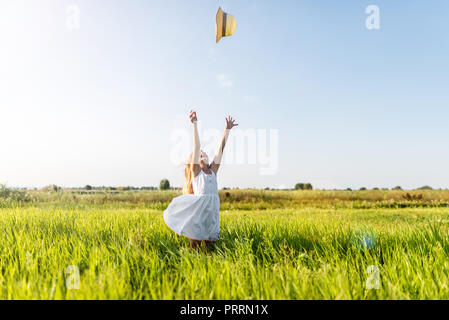 adorable little child in white dress throwing hat on field Stock Photo