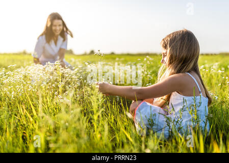 mother and daughter spending time together in green meadow on sunset Stock Photo