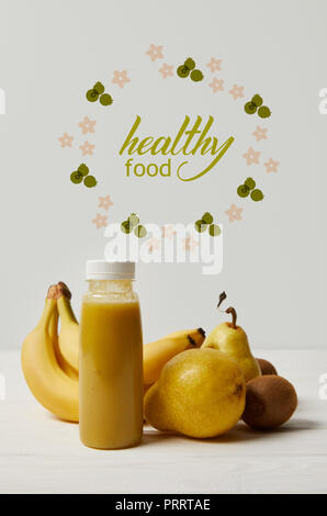 yellow detox smoothie in bottles with bananas, pears and kiwis on white background, healthy food inscription