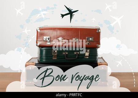 Stacked old leather travel bags with airplanes and Bon voyage (have a nice trip) inspiration Stock Photo