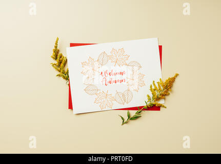 flat lay with of wildflowers and white card with 'welcome autumn' lettering on beige backdrop Stock Photo