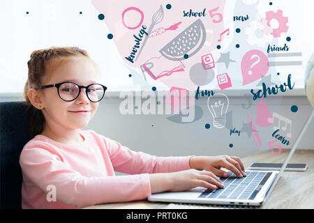 Beautiful kid in eyeglasses using laptop with educational icons Stock Photo