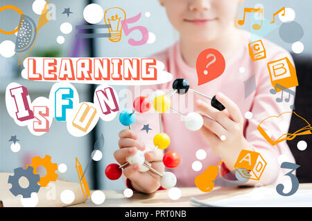 cropped shot of smiling schoolchild holding molecular model, with icons and lettering "learning is fun" Stock Photo