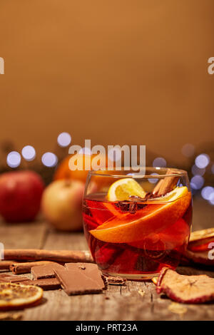 close up view of mulled wine drink, chocolate and spices on wooden surface with bokeh lights on background Stock Photo
